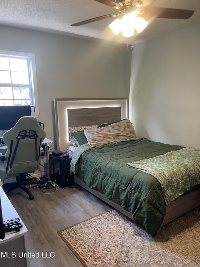 bedroom featuring ceiling fan, a textured ceiling, and wood finished floors