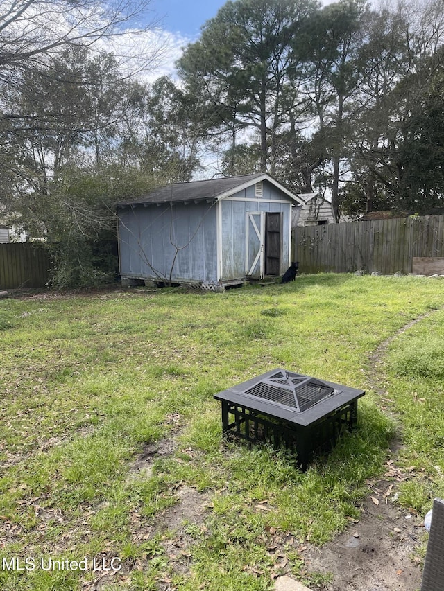 view of yard featuring an outdoor fire pit, a fenced backyard, an outdoor structure, and a shed