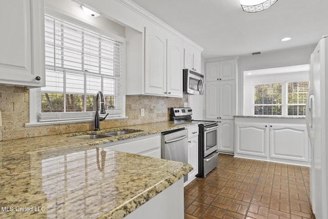 kitchen with white cabinets, light stone countertops, appliances with stainless steel finishes, and tasteful backsplash