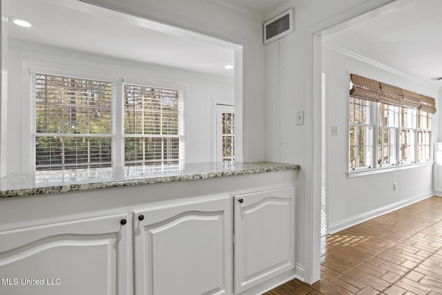 kitchen with a healthy amount of sunlight, white cabinetry, and light stone counters