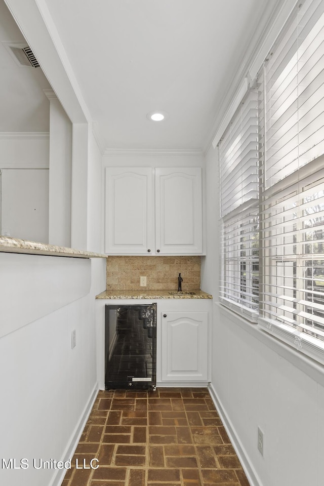 bar featuring backsplash, wine cooler, crown molding, and white cabinets