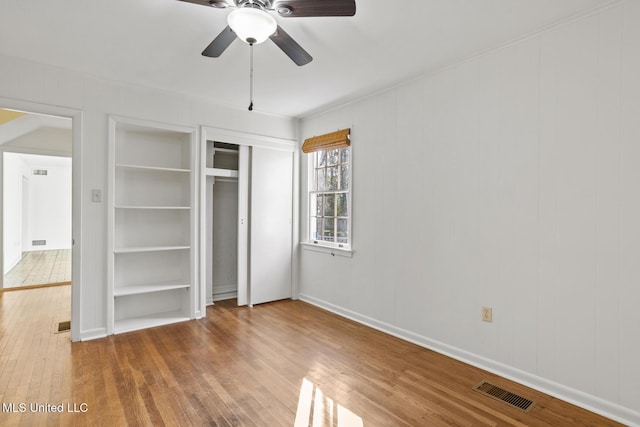 unfurnished bedroom featuring hardwood / wood-style floors, a closet, and ceiling fan