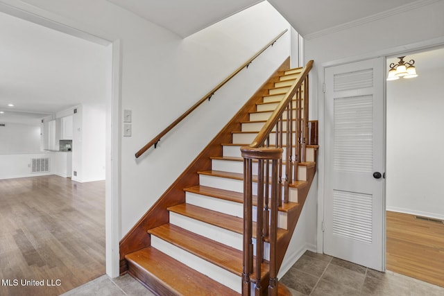 staircase featuring a notable chandelier and crown molding