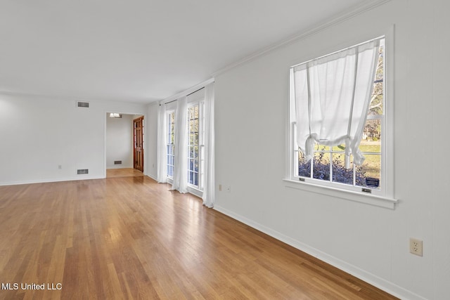 empty room featuring ornamental molding and light hardwood / wood-style flooring