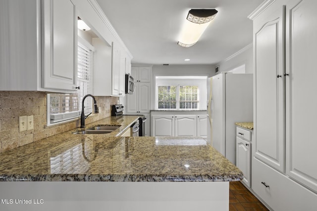 kitchen with kitchen peninsula, stainless steel appliances, dark stone counters, and sink