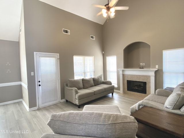 living room with light wood-style floors, visible vents, a fireplace, and baseboards