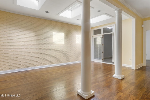 empty room featuring brick wall, baseboards, ornamental molding, and dark wood finished floors