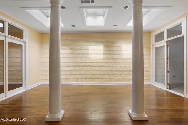 exercise room with ornamental molding, brick wall, wood finished floors, and baseboards