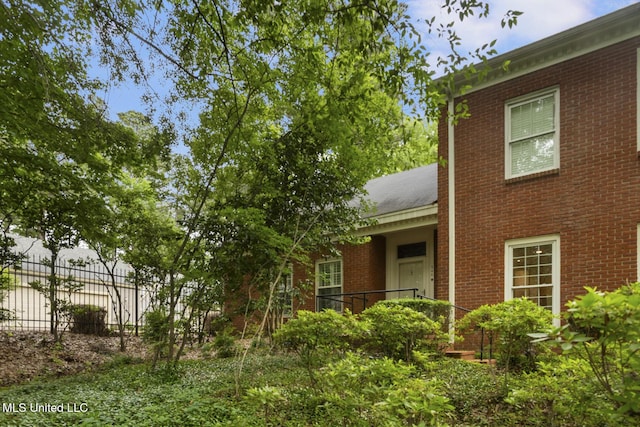 view of home's exterior with brick siding and fence
