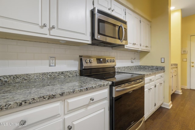 kitchen featuring appliances with stainless steel finishes, dark wood-style floors, white cabinetry, tasteful backsplash, and baseboards