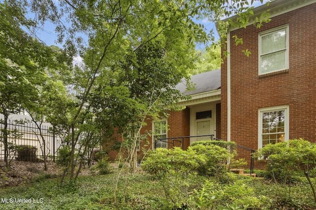view of front facade featuring brick siding and fence