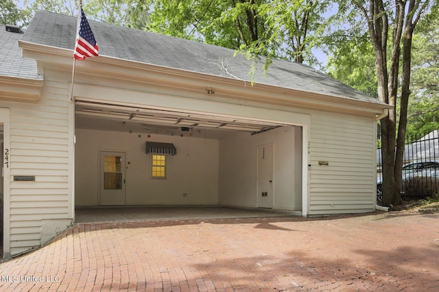 garage featuring decorative driveway and fence
