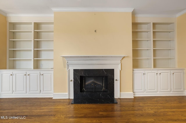 unfurnished living room featuring dark wood-style floors, crown molding, a fireplace, built in shelves, and baseboards