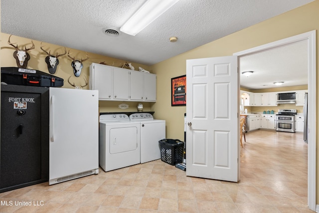 laundry room featuring cabinets, washer and dryer, and a textured ceiling