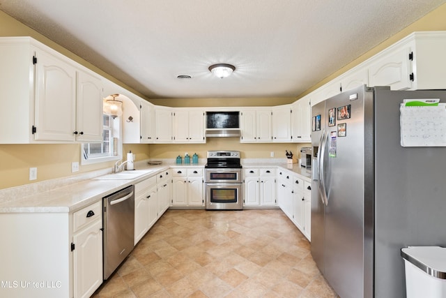 kitchen with sink, white cabinets, stainless steel appliances, and a textured ceiling