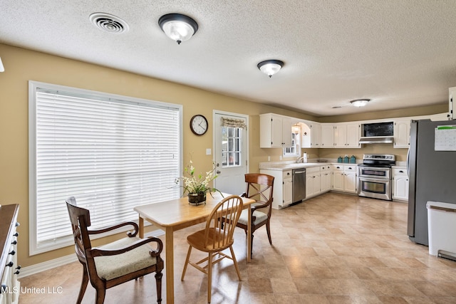 kitchen with white cabinets, sink, wall chimney exhaust hood, a textured ceiling, and appliances with stainless steel finishes