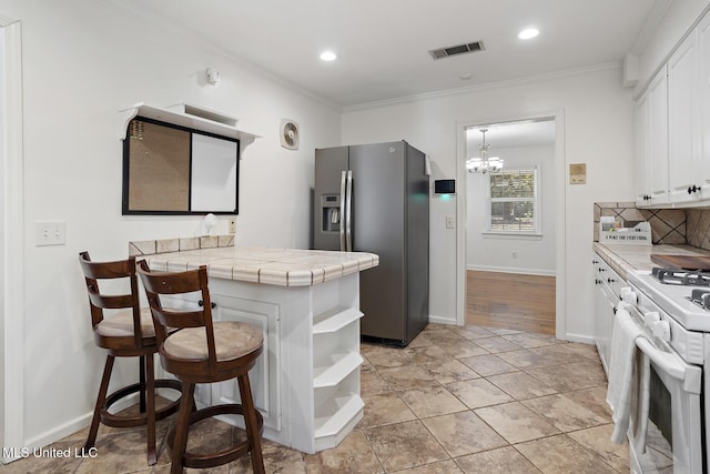 kitchen with white cabinets, stainless steel refrigerator with ice dispenser, tile counters, open shelves, and white gas range