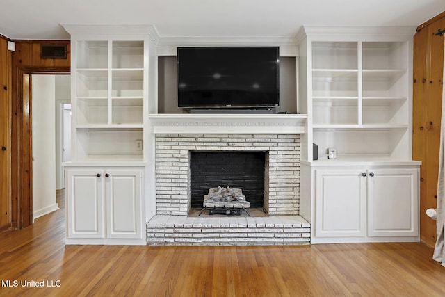 unfurnished living room featuring a brick fireplace, visible vents, and light wood-style floors