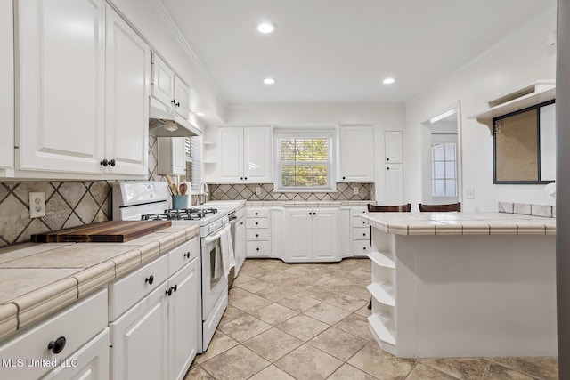 kitchen featuring open shelves, white gas range oven, tile counters, and white cabinets