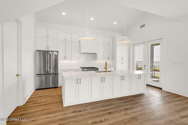 26470 W Beach Blvd, Pass Christian, MS 39571 - kitchen featuring high end fridge, vaulted ceiling, white cabinets, light countertops, and light wood-style flooring