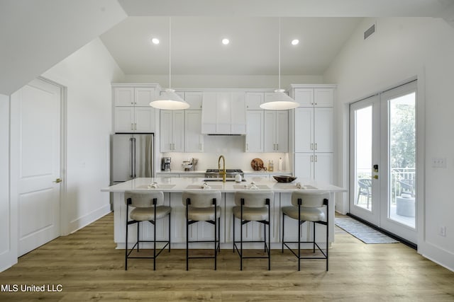26470 W Beach Blvd, Pass Christian, MS 39571 - kitchen with stainless steel refrigerator, lofted ceiling, a center island with sink, white cabinetry, and premium range hood