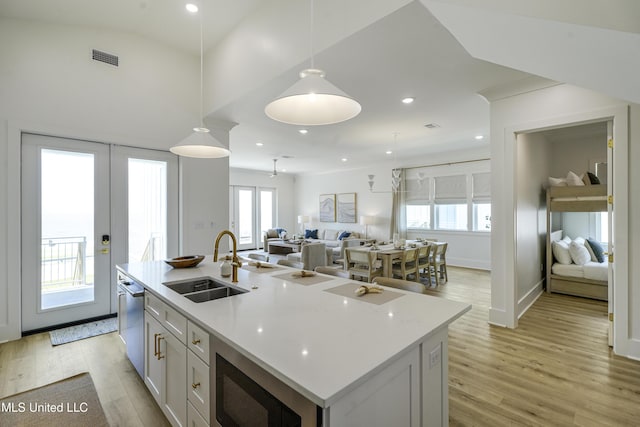 26470 W Beach Blvd, Pass Christian, MS 39571 - kitchen with stainless steel appliances, light wood-style floors, pendant lighting, a kitchen island with sink, and french doors