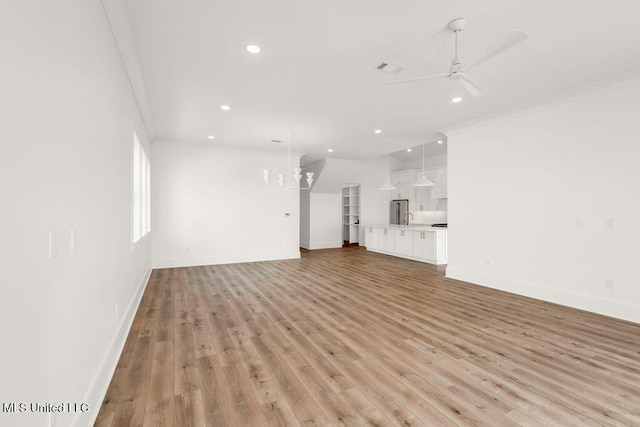 26470 W Beach Blvd, Pass Christian, MS 39571 - unfurnished living room featuring crown molding, a ceiling fan, recessed lighting, light wood-style floors, and a chandelier
