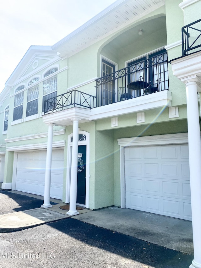 2252 Beach Dr Unit 203, Gulfport, MS 39507 - view of side of home featuring a garage, a balcony, stucco siding, and asphalt driveway