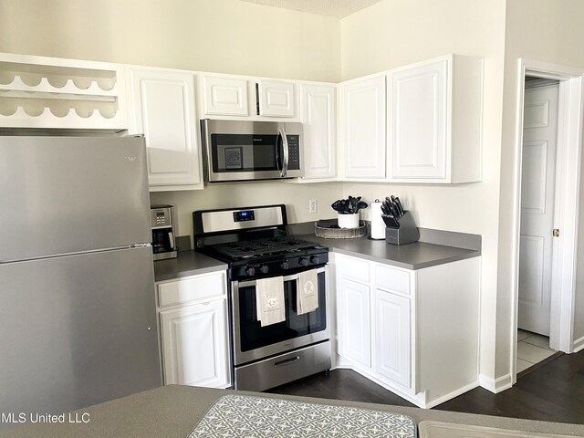 2252 Beach Dr Unit 203, Gulfport, MS 39507 - kitchen featuring appliances with stainless steel finishes, white cabinets, dark wood finished floors, dark countertops, and open shelves