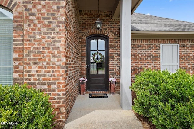 property entrance with roof with shingles and brick siding