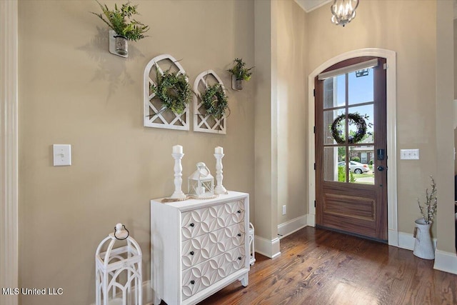 foyer entrance featuring arched walkways, baseboards, and wood finished floors