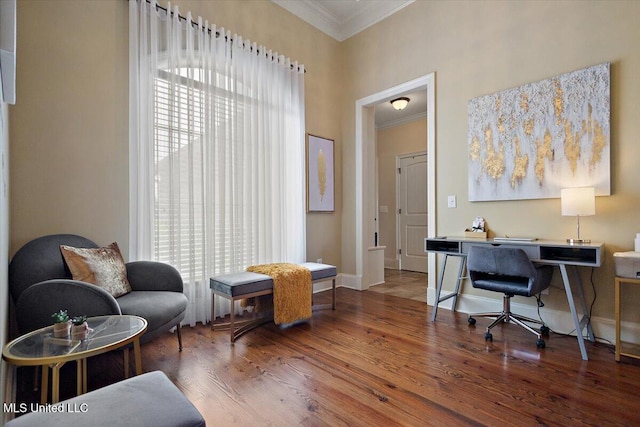 office space with crown molding, baseboards, a towering ceiling, and wood finished floors