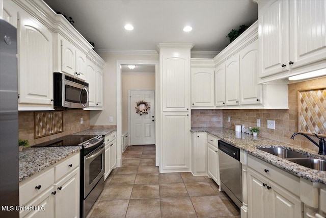 kitchen with crown molding, white cabinetry, a sink, appliances with stainless steel finishes, and backsplash