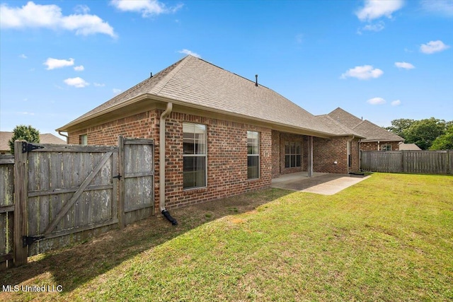 back of house featuring roof with shingles, brick siding, a fenced backyard, a yard, and a patio