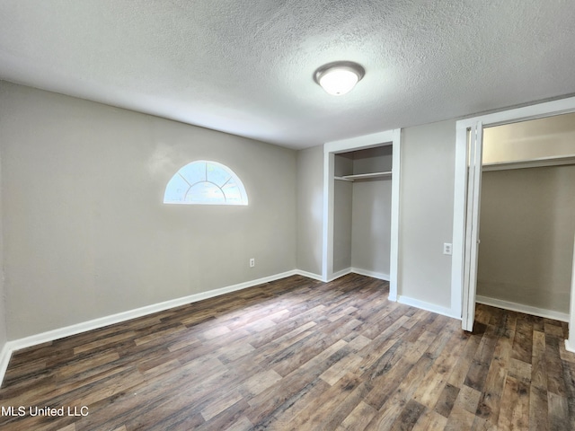 unfurnished bedroom with a textured ceiling and dark hardwood / wood-style flooring