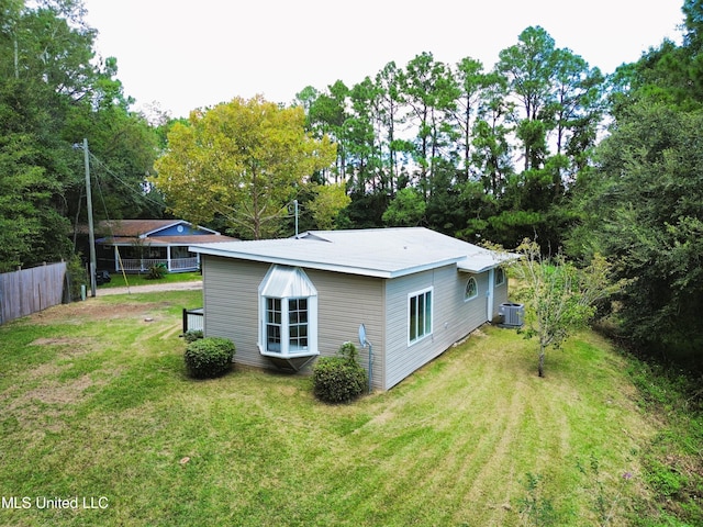 back of house featuring central AC unit and a lawn