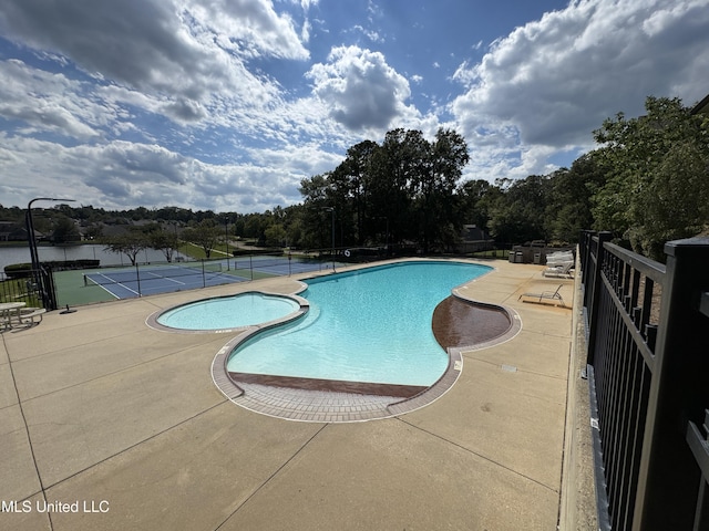 view of pool featuring tennis court and a water view