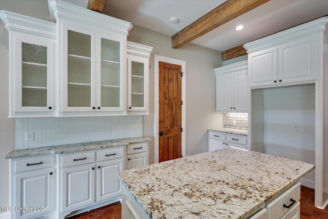 kitchen with decorative backsplash, white cabinetry, light stone counters, and beamed ceiling