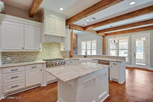 kitchen with sink, a center island, stainless steel gas cooktop, beamed ceiling, and hanging light fixtures