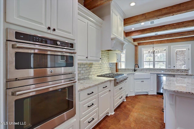 kitchen featuring hanging light fixtures, stainless steel appliances, a notable chandelier, white cabinets, and sink