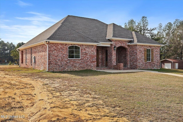 view of front facade featuring a front lawn, a garage, and an outbuilding