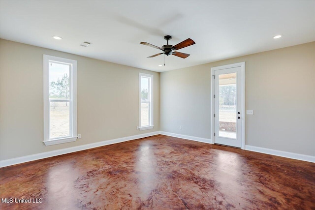 empty room featuring concrete floors, ceiling fan, and a wealth of natural light