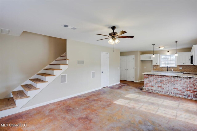 unfurnished living room featuring ceiling fan and sink