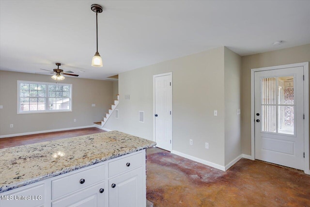 kitchen with white cabinets, light stone counters, ceiling fan, and hanging light fixtures