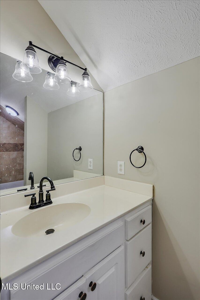 bathroom featuring a textured ceiling, vaulted ceiling, and vanity