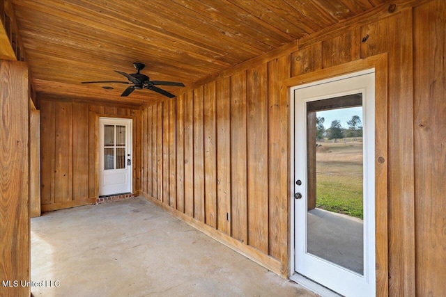 interior space with wooden walls, wooden ceiling, and ceiling fan