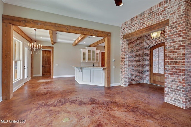 unfurnished living room featuring brick wall, an inviting chandelier, plenty of natural light, and beamed ceiling