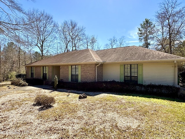 ranch-style house featuring brick siding and roof with shingles