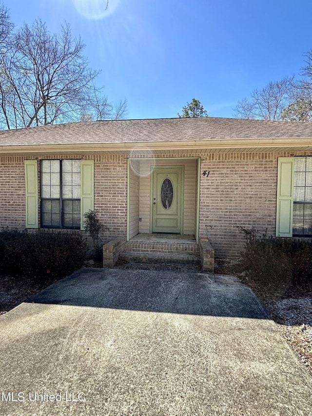 property entrance with brick siding and roof with shingles