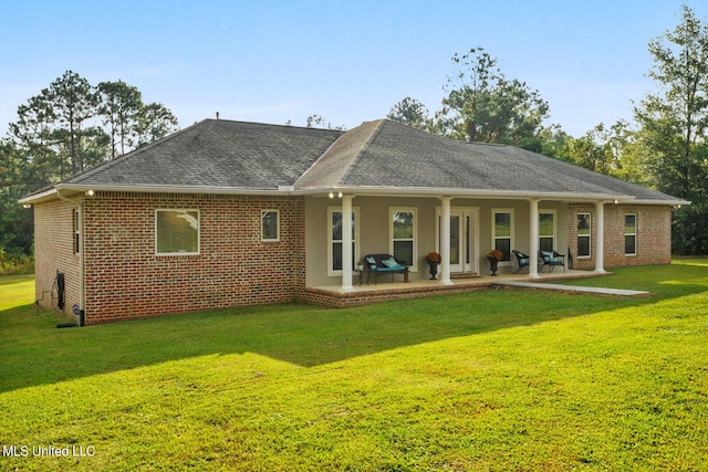 back of property with a patio area, brick siding, a yard, and roof with shingles